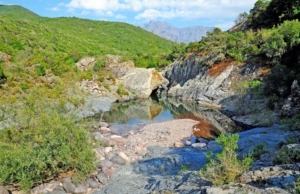 Fango river imersed in green maquis with the backdrop of Corsica's highest mountains.