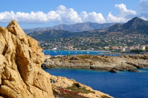 A town of L'Ile-Rousse set against majestic mountains on the coast of the Mediterranean sea.