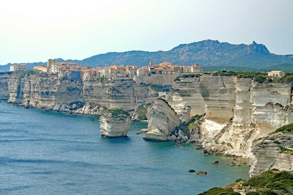Bonifacio perches dramatically atop towering white limestone cliffs, overlooking the sparkling Mediterranean and sea caves below.