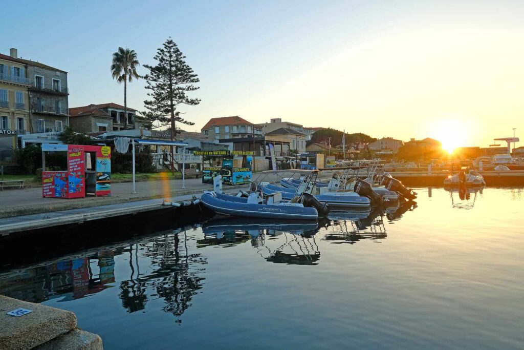 As the sun sets, the Propriano marina glows with warm reflections rippling across the water and boats.