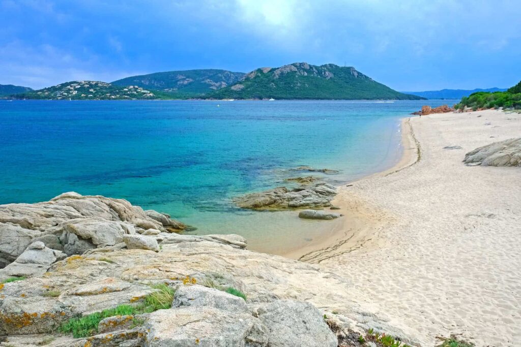 A haven of tranquillity, Cala Rossa captivates with its red rocks, deep emerald sea, and soft golden sands.