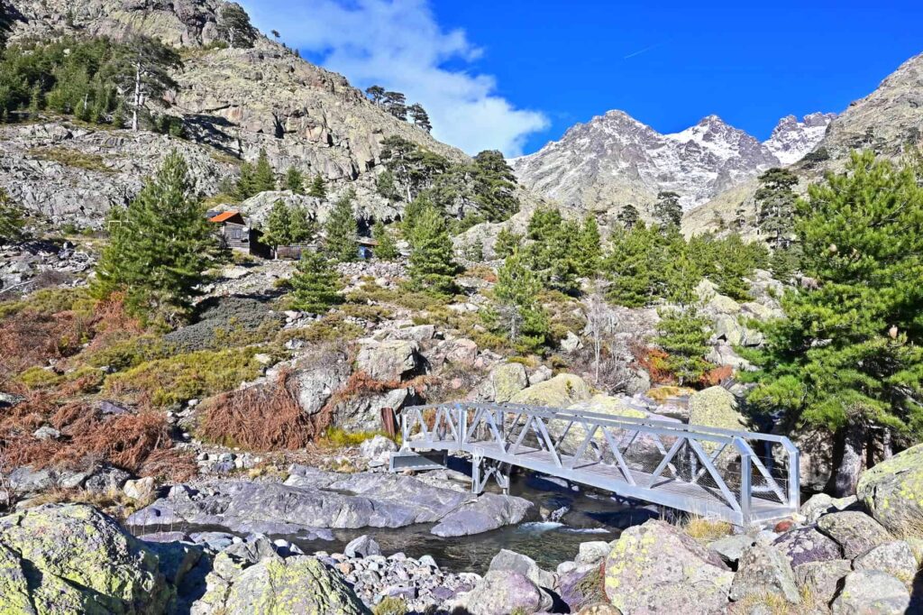 Just before Bergerie de Ballone, a small metal bridge arcs over a stream with awe-inspiring mountain views.